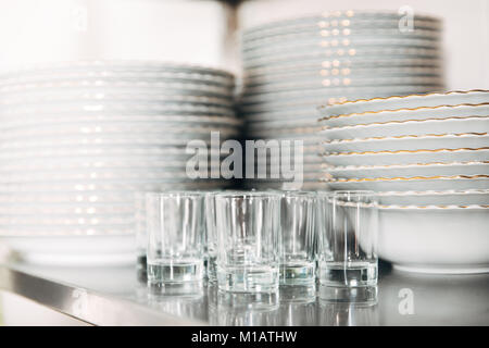 close-up shot of stacked clean tableware and glasses at restaurant Stock Photo
