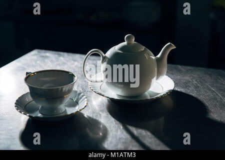 vintage teapot an cup on metal surface in dark room Stock Photo