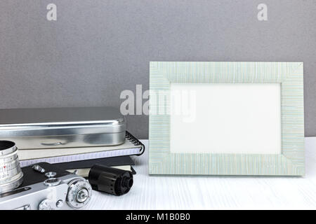 retro camera, notebook, negative film roll and empty photo frame on grey wall background Stock Photo