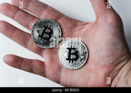 Two silver bitcoin in the hand on white background. Digital currency. Stock Photo