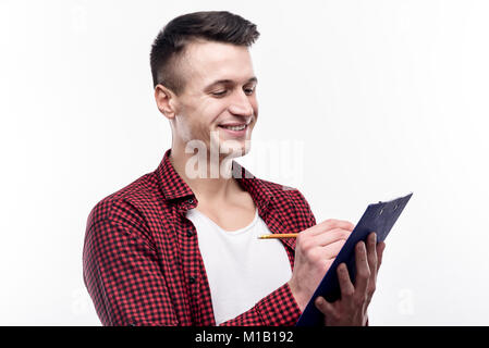 Charming young man making notes on sheet holder Stock Photo