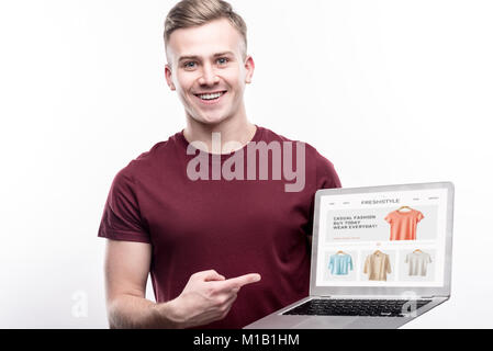 Charming man showing website of online clothes shop Stock Photo