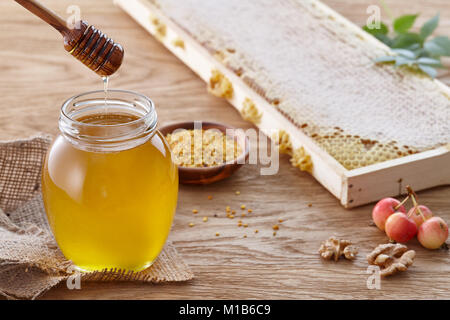 Honey jar, bee pollen and honeycombs on wooden table Stock Photo