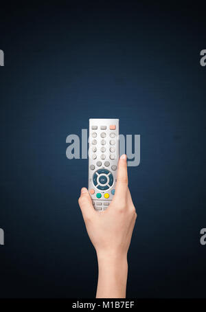 Hand holding a remote control on blue background Stock Photo
