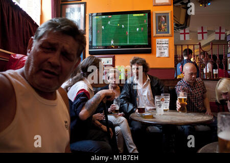 Locals at the Queens Head pub, Burlslem, Stoke-on Trent, watch the England World Cup match versus Slovenia, 23rd June 2010. Burslem was once the Mother town of the ceramic and pottery industry, but now only a few of the Pot Banks are fuctioning as most of the industry has moved to the far east. Rich Bowen Photography Stock Photo