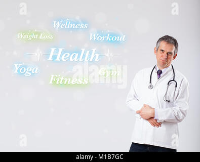 Elderly clinical doctor pointing to health and fitness collection of words Stock Photo