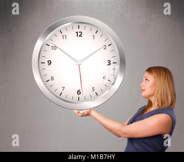 Attractive young lady holding a huge clock Stock Photo