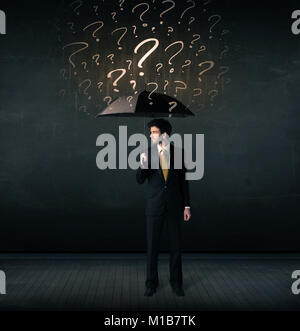 Businessman with umbrella and a lot of drawn question marks concept on background Stock Photo