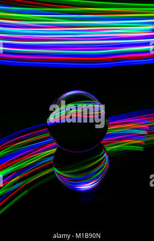 Light painting with a crystal ball placed on a glass surface and using coloured led lights as a light source.