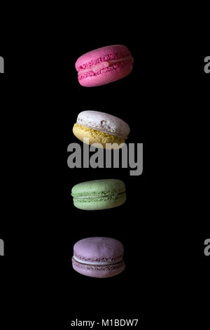 Multicolored macaroons falling or flying isolated on black background Stock Photo