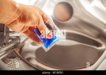 blue gel caps in hand for washing mashine, liquid coloured detergent