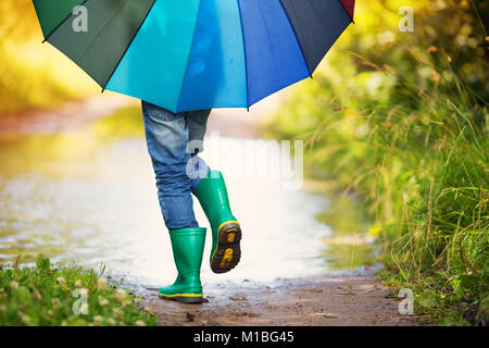 Child walking in wellies in puddle on rainy weather Stock Photo