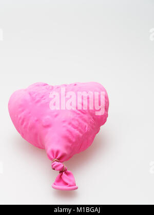 Deflate heart shape balloon in pink color isolated on white background Stock Photo