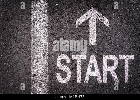 Word Start and an arrow written on an asphalt road background Stock Photo