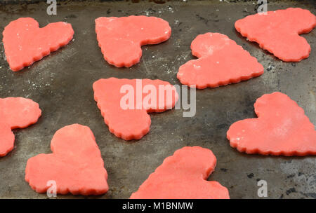 Close up of raw red valentines cookies on baking sheet in preparation for Valentines Day Stock Photo