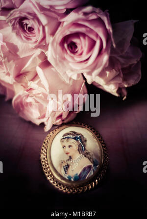 vintage brooch with painted miniature of a wealthy lady with pink roses Stock Photo