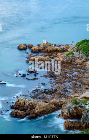 Long exposure with blurred water of a lighthouse on a rock at the entrance to the Knysna lagoon. Knysna is a popular stop along the Garden Route in So Stock Photo