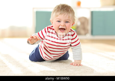 Front view portrait of a joyful baby crawling towards camera on the floor at home Stock Photo