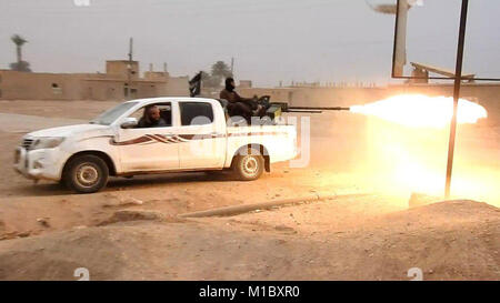 Still image captured from Islamic State propaganda video showing ISIS fighters firing a heavy machine gun from the back of a pickup truck during fighting north of Al-Bahrah against the Syrian Army January 25, 2018 near Deir ez-Zor, Syria. Stock Photo