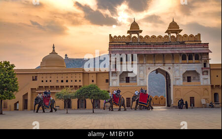 Tourists enjoy elephant ride at Amer Fort Jaipur Rajasthan at sunrise. Amber Fort is a UNESCO World Heritage site Stock Photo