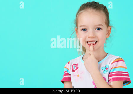 Adorable little girl smiling and showing off her first lost milk tooth. Cute preschooler portrait after dropping her front baby tooth. Stock Photo