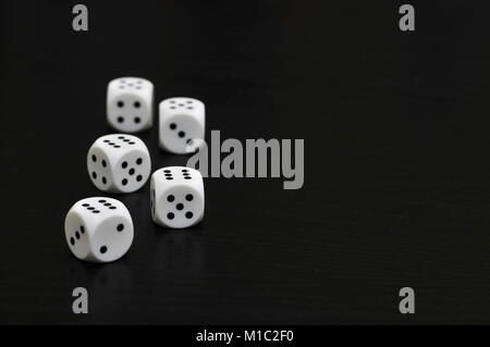 Five white dice on black table. Stock Photo