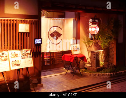 Mitoko, traditional Japanese Kaiseki restaurant lit by the lights of lanterns at night with a Noren curtain in the entrance door and menus displayed o Stock Photo
