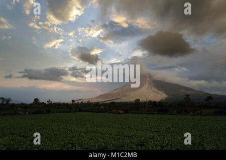 Colourful Sunset over Sinabung volcano in the Karo Highlands of North Sumatra, Indonesia. This is a highly active volcano. Stock Photo