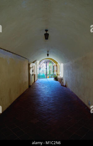 An old medieval stone tunnel under fortress wall with a garden and light at the end Stock Photo