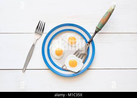 Fried Quail Eggs on a cornishware plate with a vintage spatula and fork from above Stock Photo