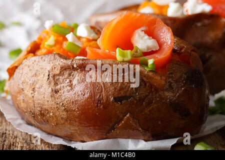 Baked whole sweet potatoes stuffed with salmon and onions macro on a table. horizontal Stock Photo