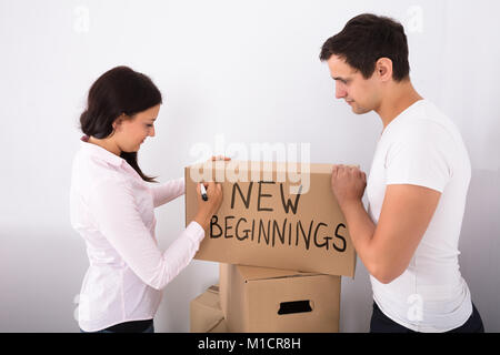 Man Looking At Woman Writing On Cardboard Box New Beginnings With Marker Stock Photo