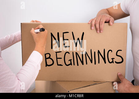 Close-up Of Woman Writing New Beginnings With Marker On Cardboard Box Stock Photo