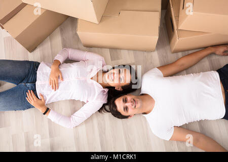 Elevated View Of Happy Young Couple Lying On Hardwood Floor Stock Photo