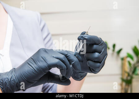 Dermatologist doctor with syringe planning beauty facial injections. Face aging, rejuvenation, mesotherapy and hydration procedures. Aesthetic cosmetology. Selective focus. Stock Photo