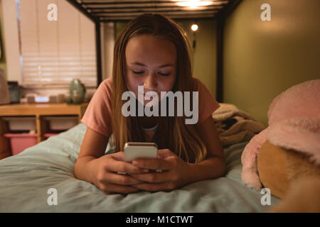 Girl lying on bed using her mobile phone Stock Photo