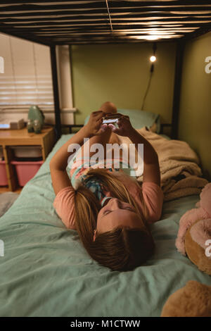 Girl lying on bed using her mobile phone Stock Photo
