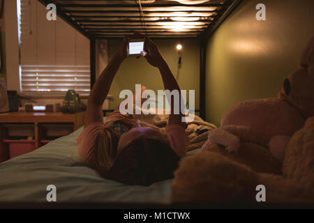 Girl lying on bed using her mobile phone Stock Photo
