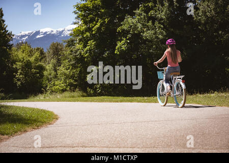 Girl wearing safety helmet riding bicycle on road on a sunny day Stock Photo