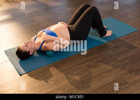 Pregnant woman performing yoga in living room Stock Photo