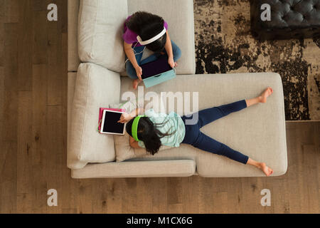 Siblings with headphones using digital tablet at home Stock Photo
