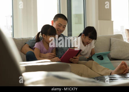 Girls using digital tablet with her father in living room Stock Photo