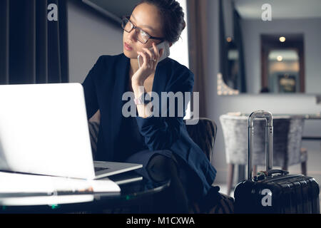 Woman talking on mobile phone while using laptop Stock Photo