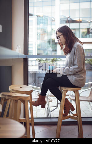 Thoughtful woman having coffee at table Stock Photo