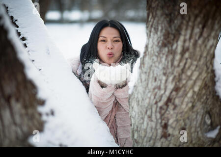 Asian blowing snow in the palms and having fun. Stock Photo