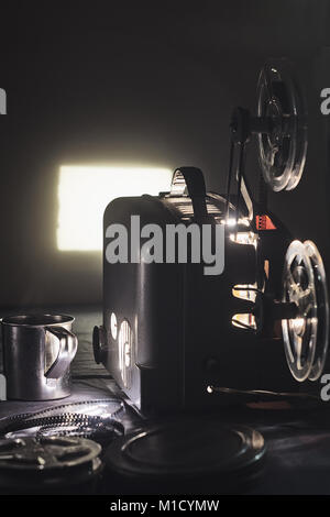 Old film projector and a glowing screen in the dark Stock Photo