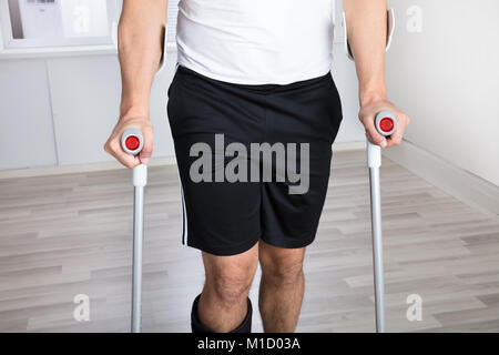 Mid Section View Of A Disabled Person With Crutches In Clinic Stock Photo
