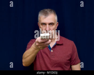 Man pointing remote control, front studio shot on blue Stock Photo