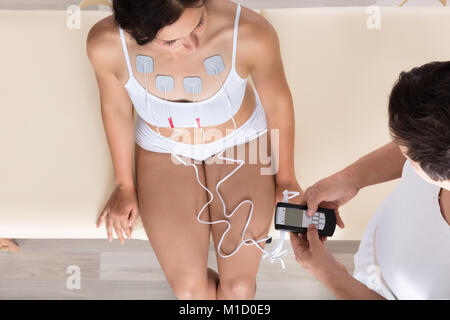 Close-up Of A Therapist's Hand Giving Electrodes Therapy To Woman Stock Photo