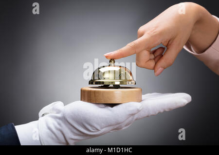 Customer Ringing Service Bell Held By Customer In Front Of Grey Background Stock Photo